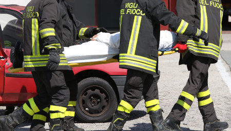 firefighters in action carry a stretcher with injured after car accident