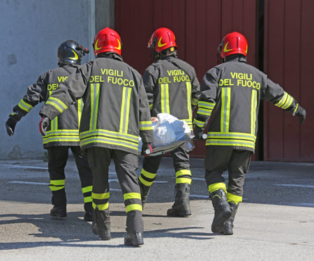 four firemen in action carry a stretcher with injured