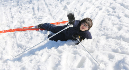 boy asks for help after the fall from snow skiing in the mountains in winterの写真素材