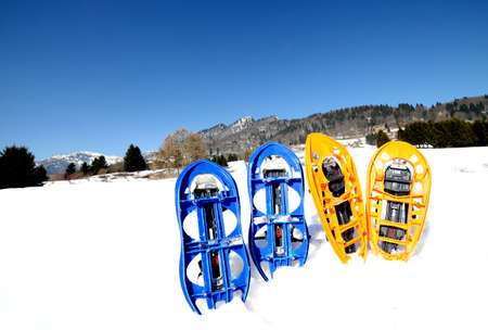 four blue and orange snowshoes in mountains in winterの写真素材