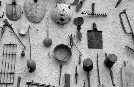 many ancient farming tools hanging on the wall of the rural Houseの写真素材