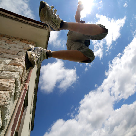 child who jumps up from the wall of the House and the clear sky
