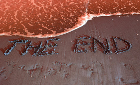 THE END written on the beach by the sea at sunset