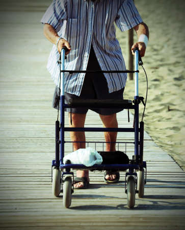 elderly man walking with Walker on the beach in summerの写真素材