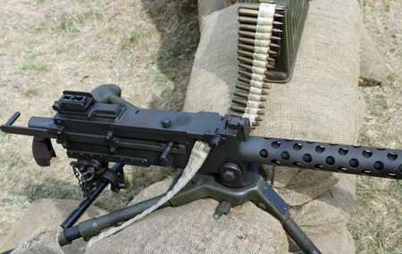 historic machine gun with bullets over the sandbags in trench warfare  used in World War II by the...