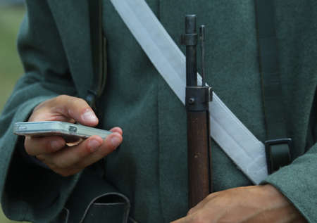 Historical re-enactment with a soldier and an anachronistic cellの写真素材