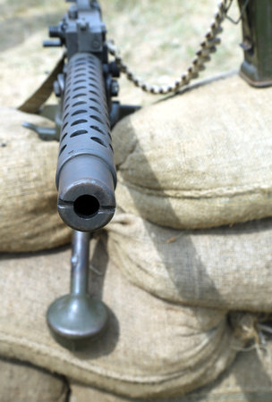 great machine gun with bullets over the sandbags in the trench war