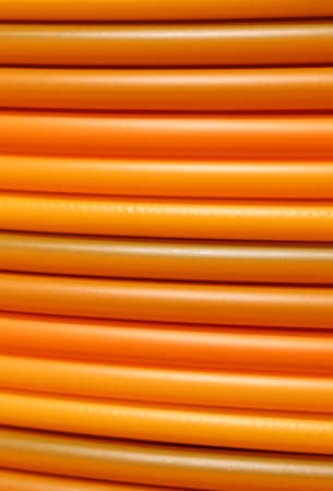 long coils of orange plastic pipes for the installation of underground utilities and energy of optical fibersの写真素材