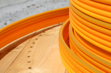long coils of orange plastic pipes for the installation of underground utilities and energy of...