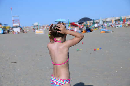 little girl plays with the bowls on the beach during the summer holidaysの写真素材