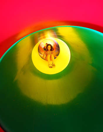 little girl on the playground comes down to one big colorful tunnel slideの写真素材