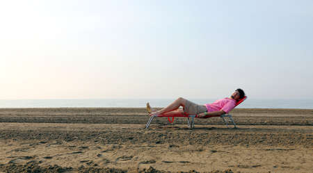 man lying on a bed by the beach by the seaの写真素材