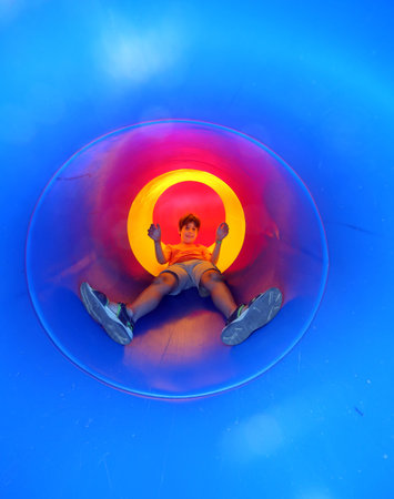 child on the playground comes down in a blue tunnel slide