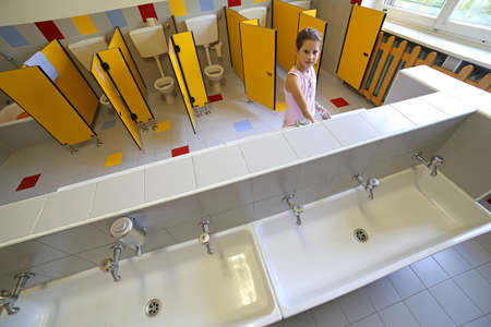 little girl is washing her hands in the bathroom of the schoolの写真素材