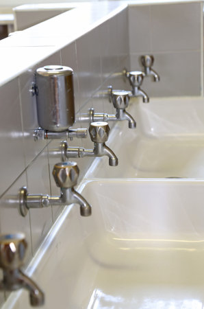 row of taps at the sink in the bathroom of school