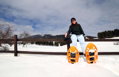 beautiful young woman with snowshoes in the snow during the winter holidays in the mountainsの写真素材