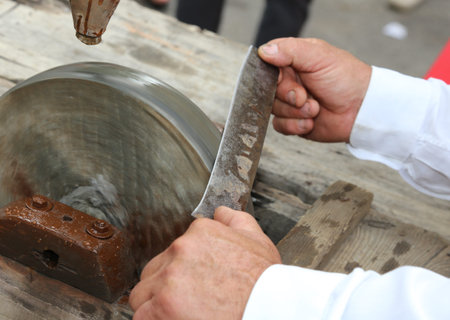 Elder while sharpening the blade of the knife on the large water wheel for sharpening