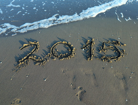 inscription year 2015 in the sand of the sea with waves on the shore