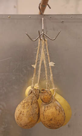 many caciocavallo cheeses hanging with special string for sale on the marketの写真素材