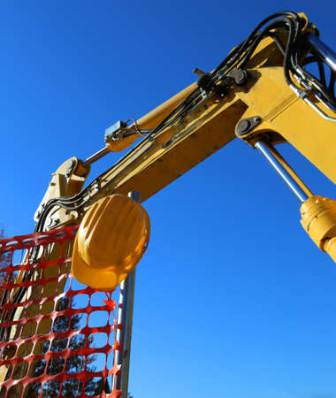 yellow hard hat on the road construction site and an excavatorの写真素材