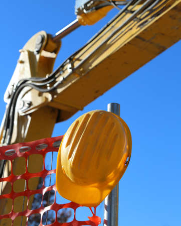 yellow hard hat on the road construction site and an excavatorの写真素材