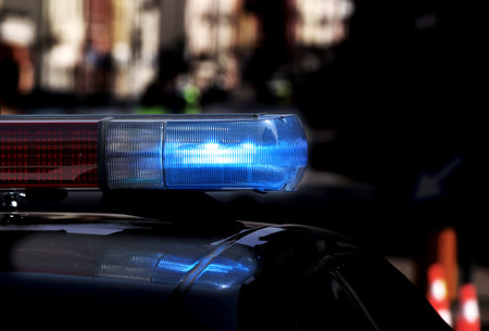 Police patrol car with flashing lights and siren on during the night raid against crime