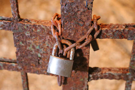 rusty padlock with the chain and the closed gate of old prisonの写真素材