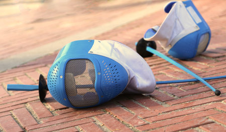 equipment fencing mask and foil resting on the ground after the defeat of the sport event