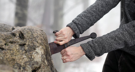 Hand of the valiant knight tries to remove the magical Excalibur sword in the stone