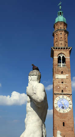 Vicenza, Italy. Ancient white stone statue over the Basilica Palladiana and the big clock towerの写真素材