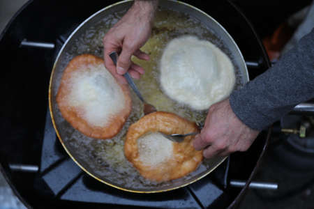 cooking fritters dipped in boiling oil in an aluminum potの写真素材