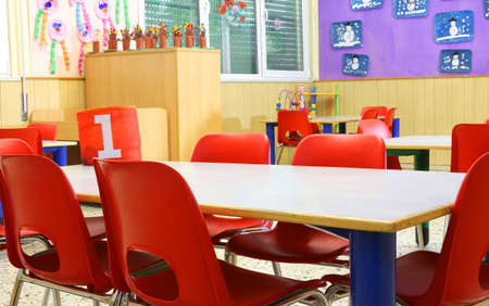 desks and small red chairs within a class of kindergarten without childrenの写真素材