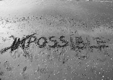 IMPOSSIBLE written with the letters IM cancelled in the wet sand of the beachの写真素材