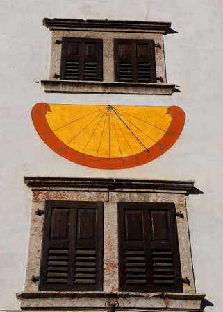 Sundial marking the hours with the shadow of the Gnomon during sunny days and two windowsの写真素材