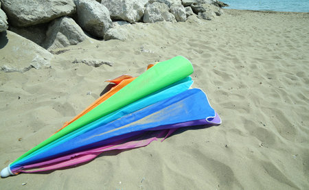 broken abandoned  parasol at the sandy beach after summer holidaysの写真素材