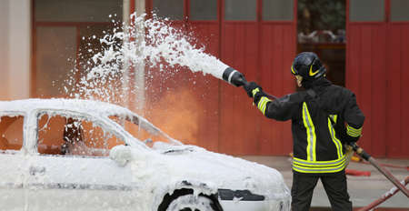 firemen during exercise to extinguish a fire in a car with foamの写真素材
