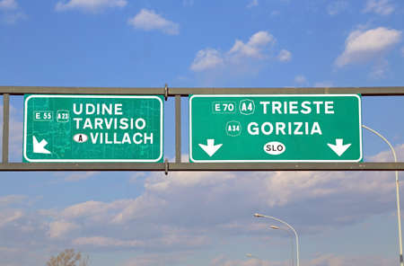 big road sign with directions to the city of Trieste and Udine in the large Italian motorwayの写真素材