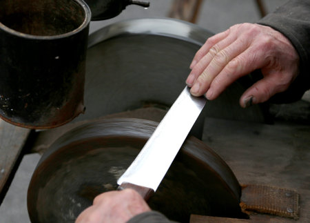 Elder grinder with hands sharpen a bladeの写真素材