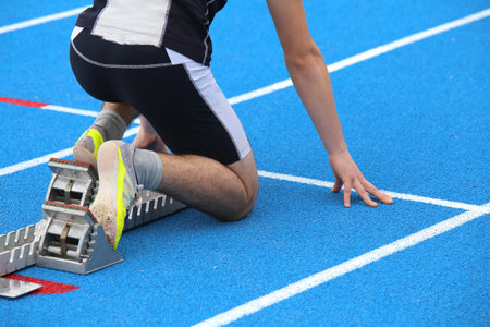 muscular young athlete in the starting blocks of a athletic track before the start of running race