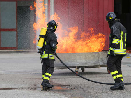 two firefighters with oxygen bottles off the fire during a training exercise in Firehouseの写真素材