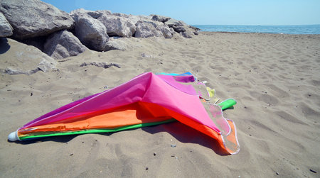 broken colored abandoned  parasol at the sandy beach after summer holidays