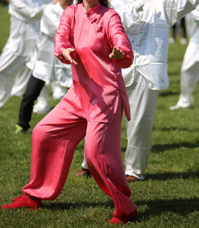 martial art Woman with pink silk dress perfectly perform the exercises in the large public park
