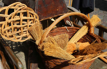 brooms of sorghum, a carpet beater and wicker containers for sale at flea marketの写真素材