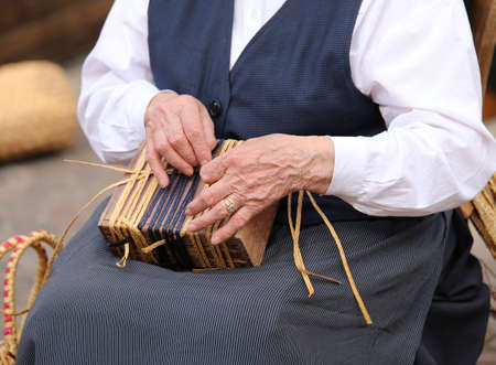 hands of an elderly woman while creating a straw bagの写真素材