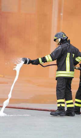 two Firefighters with hose fighting services and orange smokeの写真素材