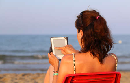 beautiful woman on chair reads the ebook on the beachの写真素材