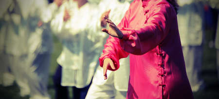 Tai Chi martial art Woman with pink silk dress perfectly perform the exercises in the large public parkの写真素材
