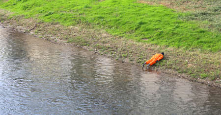 dummy of a man with orange jumpsuit on the river bank during a training exercise of civil protectionの写真素材