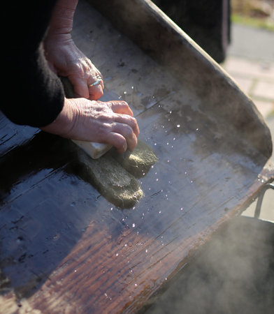 Hands of the elderly woman washing in the old wooden board