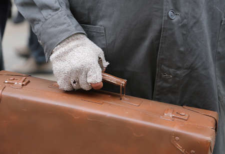 poor migrant with old leather suitcase and the broken glove during travel abroadの写真素材